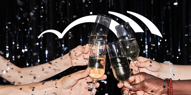 A group of people enthusiastically celebrating, each raising a champagne flute in a toast to automation, set against a dark background filled with colorful confetti cascading through the air with the BetterCloud logo in the background.