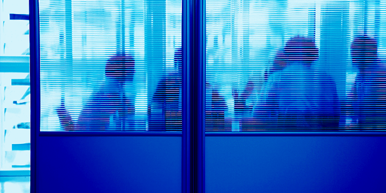 Silhouettes of several people in conversation appear blurred through frosted glass panels, creating an atmosphere of confidentiality. The ambient blue lighting surrounding the scene suggests a modern, professional setting where privacy is emphasized.